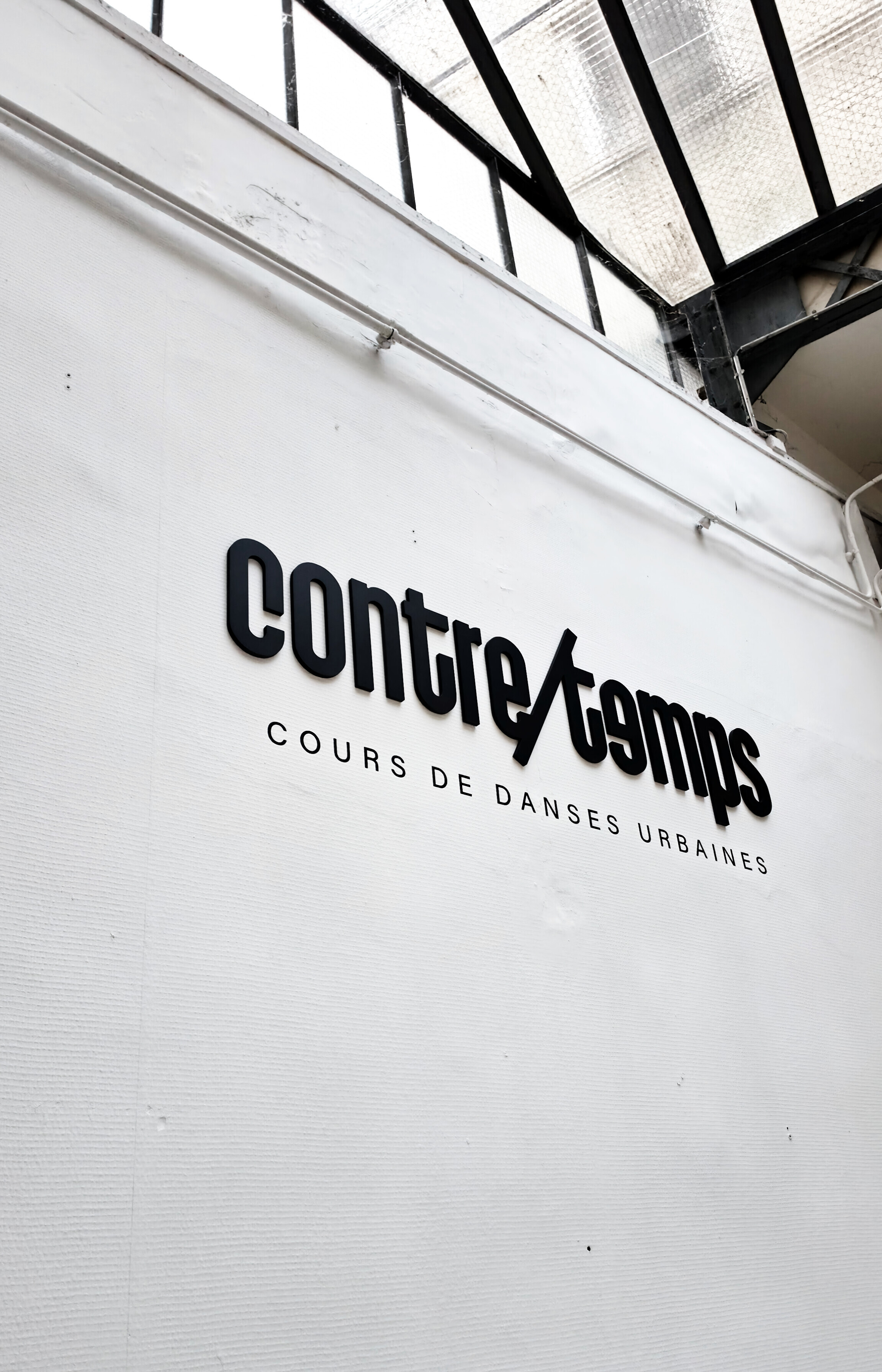 La grande salle du studio Contretemps, logo sur le mur blanc et parquet clair